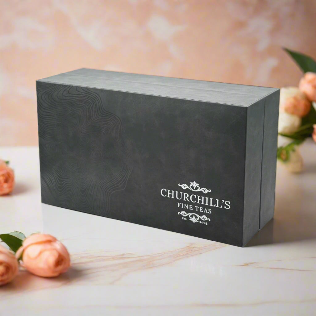 An elegant charcoal gift box with the Churchill's Fine Teas logo, containing a set of tea tins.